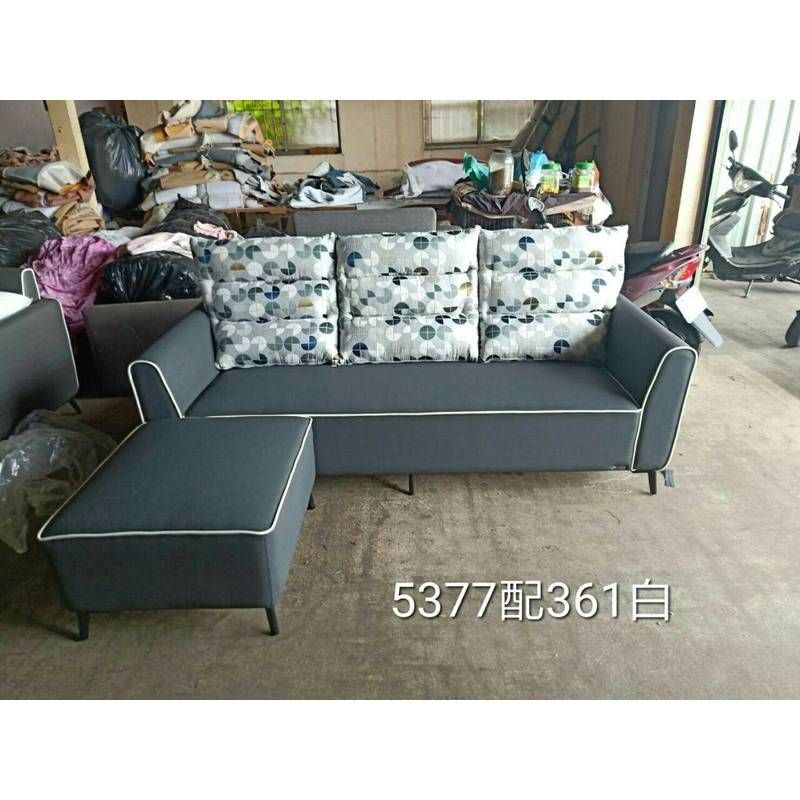 A gray couch with white pillows is sitting on a carpet in a room.