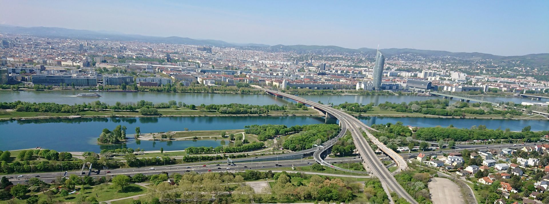 Danube River – Nature and Relaxation in Vienna Aerial view of the Danube River in Vienna, showing bridges, green parks, and modern buildings stretching across the city.