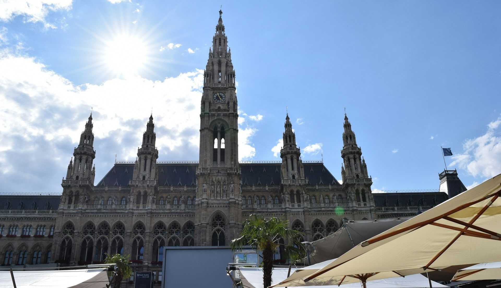 Rathausplatz – Historic Square and City Events Hub Front view of Vienna City Hall at Rathausplatz under a bright blue sky, with people and market stalls in the foreground.