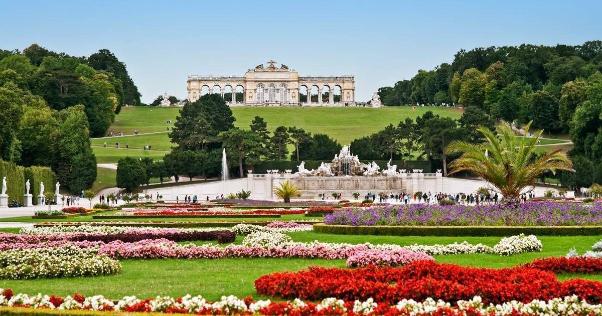 View of the Gloriette at Schönbrunn Palace with colorful flower gardens in the foreground