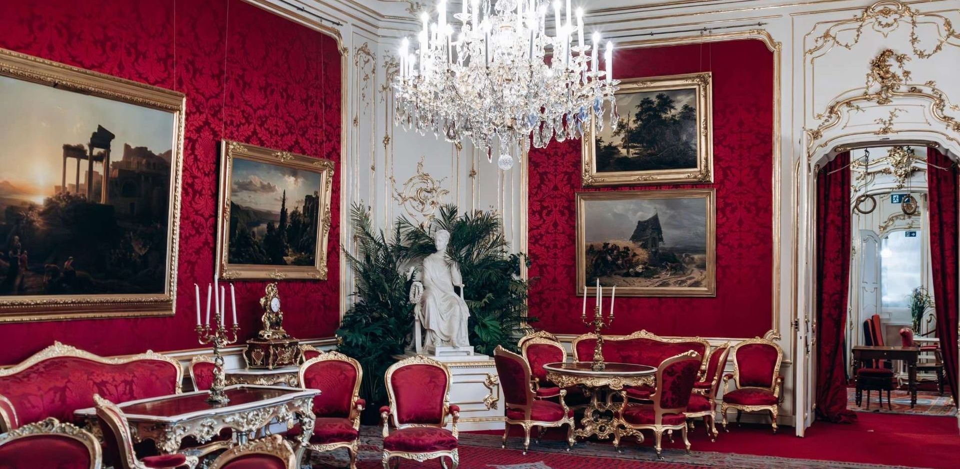 Lavish interior of the Imperial Apartments at Hofburg Palace Vienna with red walls, chandeliers, and antique furniture