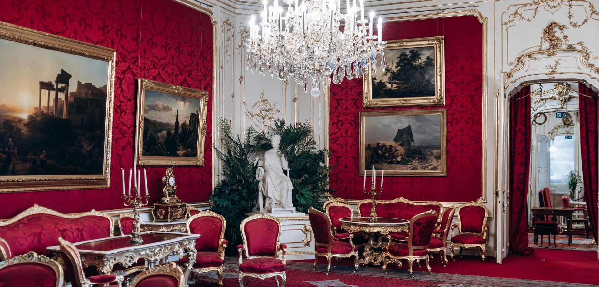 Lavish interior of the Imperial Apartments at Hofburg Palace Vienna with red walls, chandeliers, and antique furniture