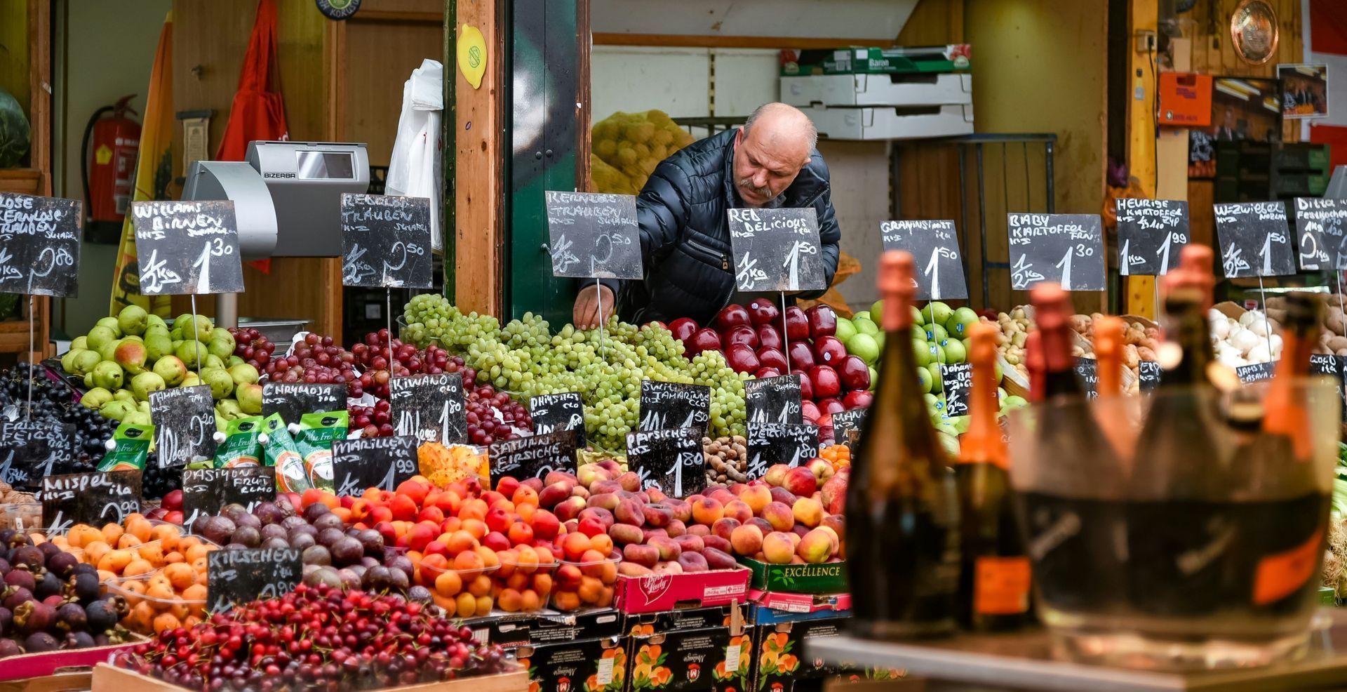 Naschmarkt – Vienna’s Most Popular Outdoor Market Colorful fruit and vegetable stands at Vienna’s Naschmarkt, with a vendor arranging produce at an open-air market.