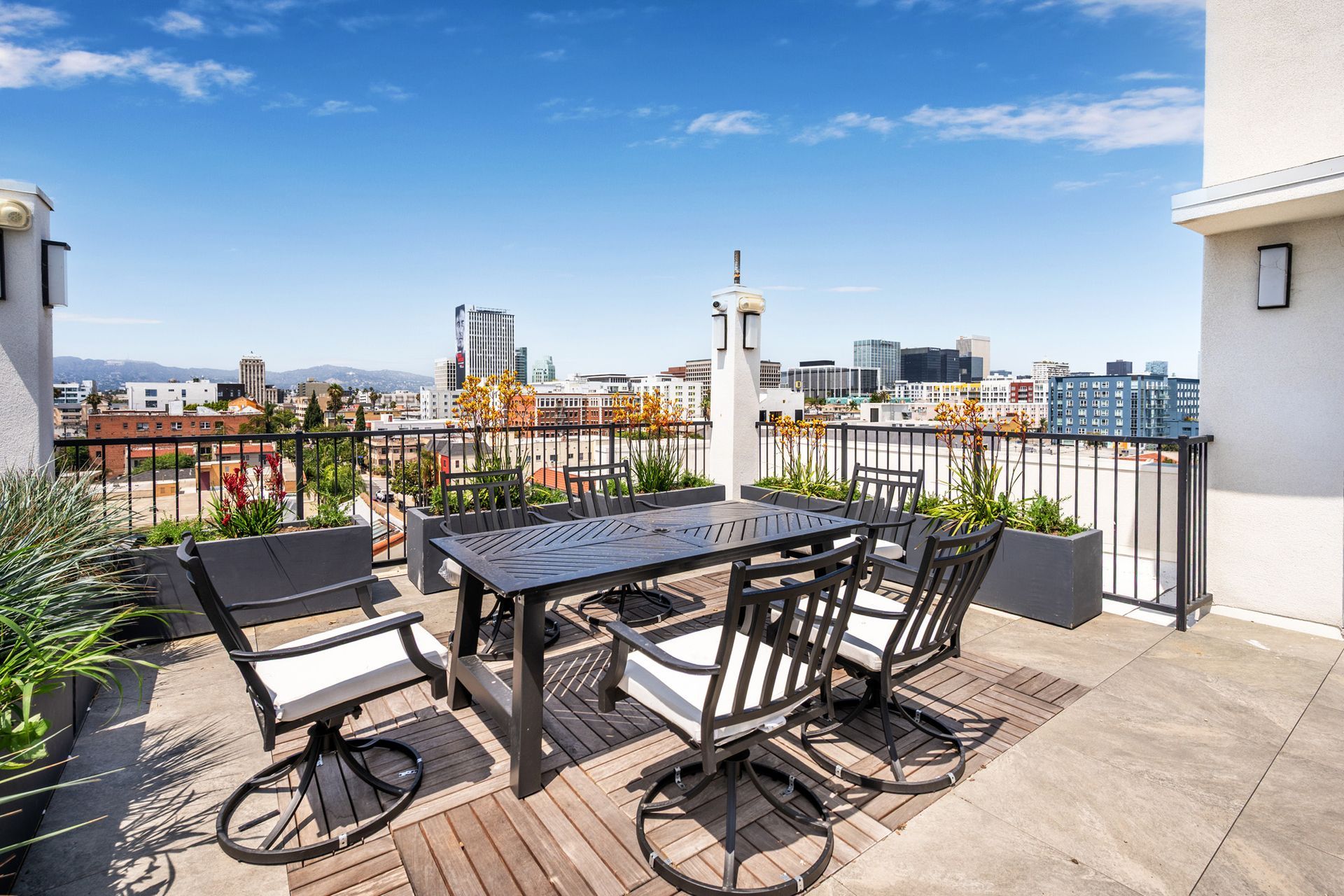 A rooftop patio with a table and chairs and a view of the city.