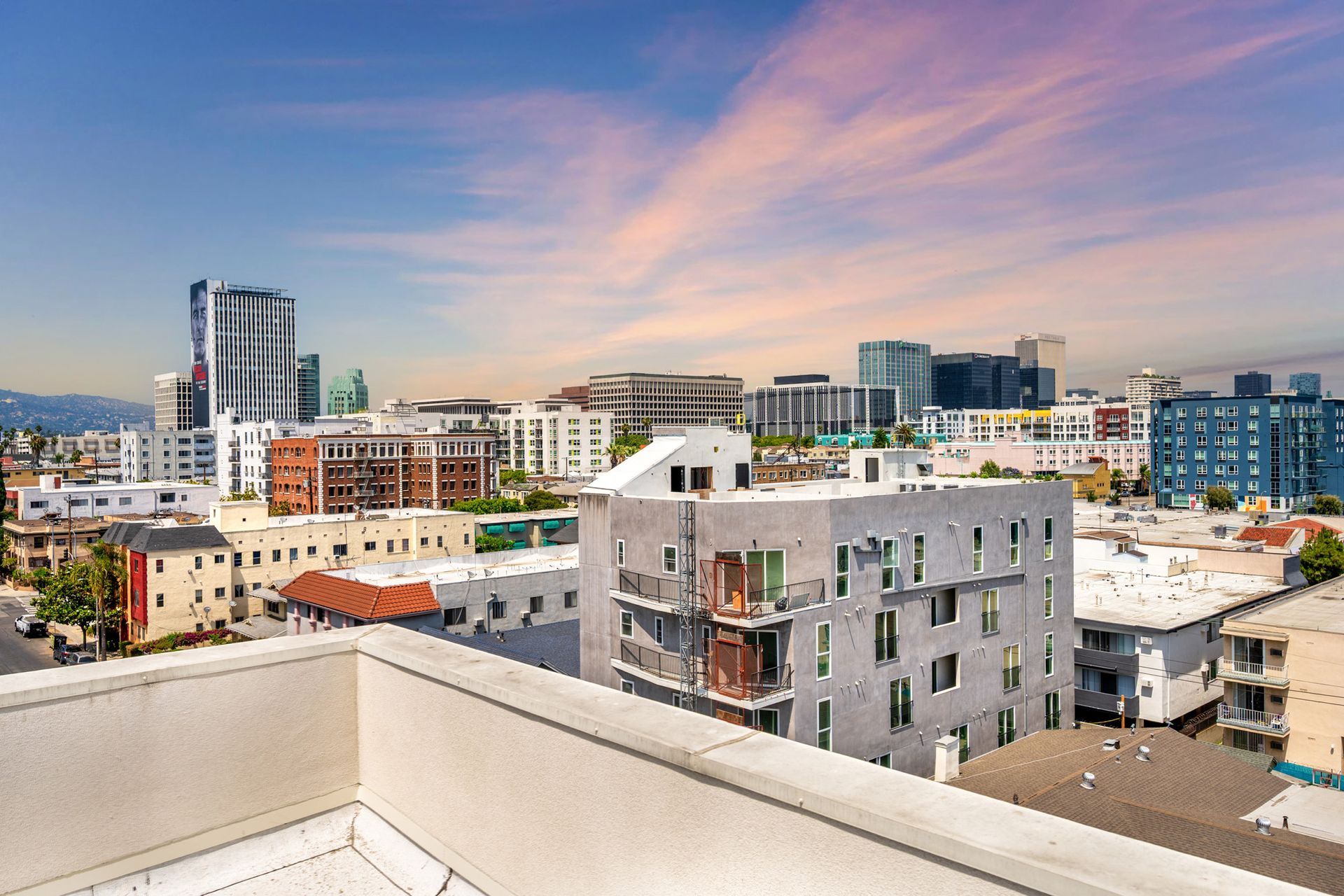A view of a city from a balcony with a sunset in the background.