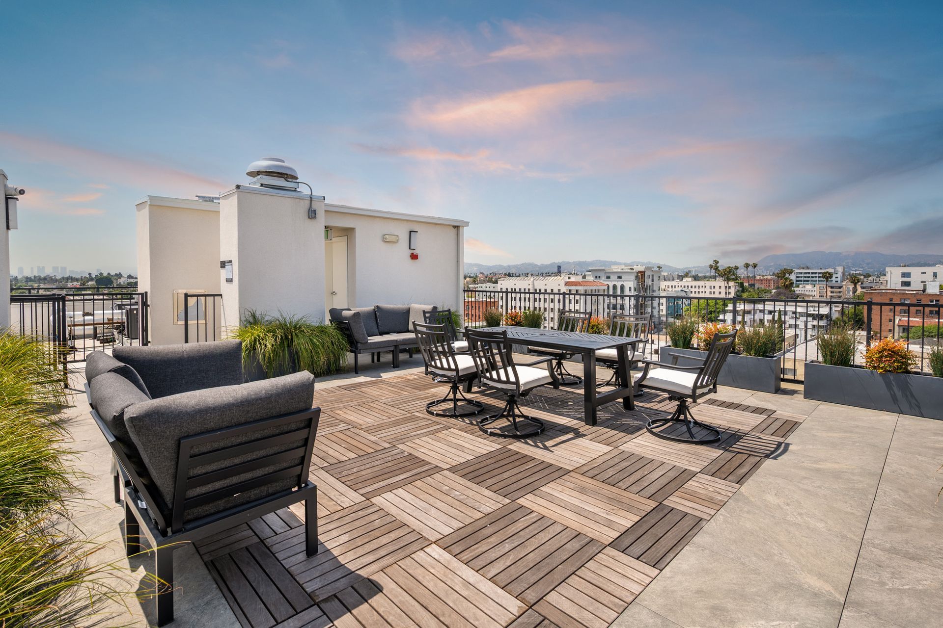A rooftop deck with a table and chairs and a view of the city.