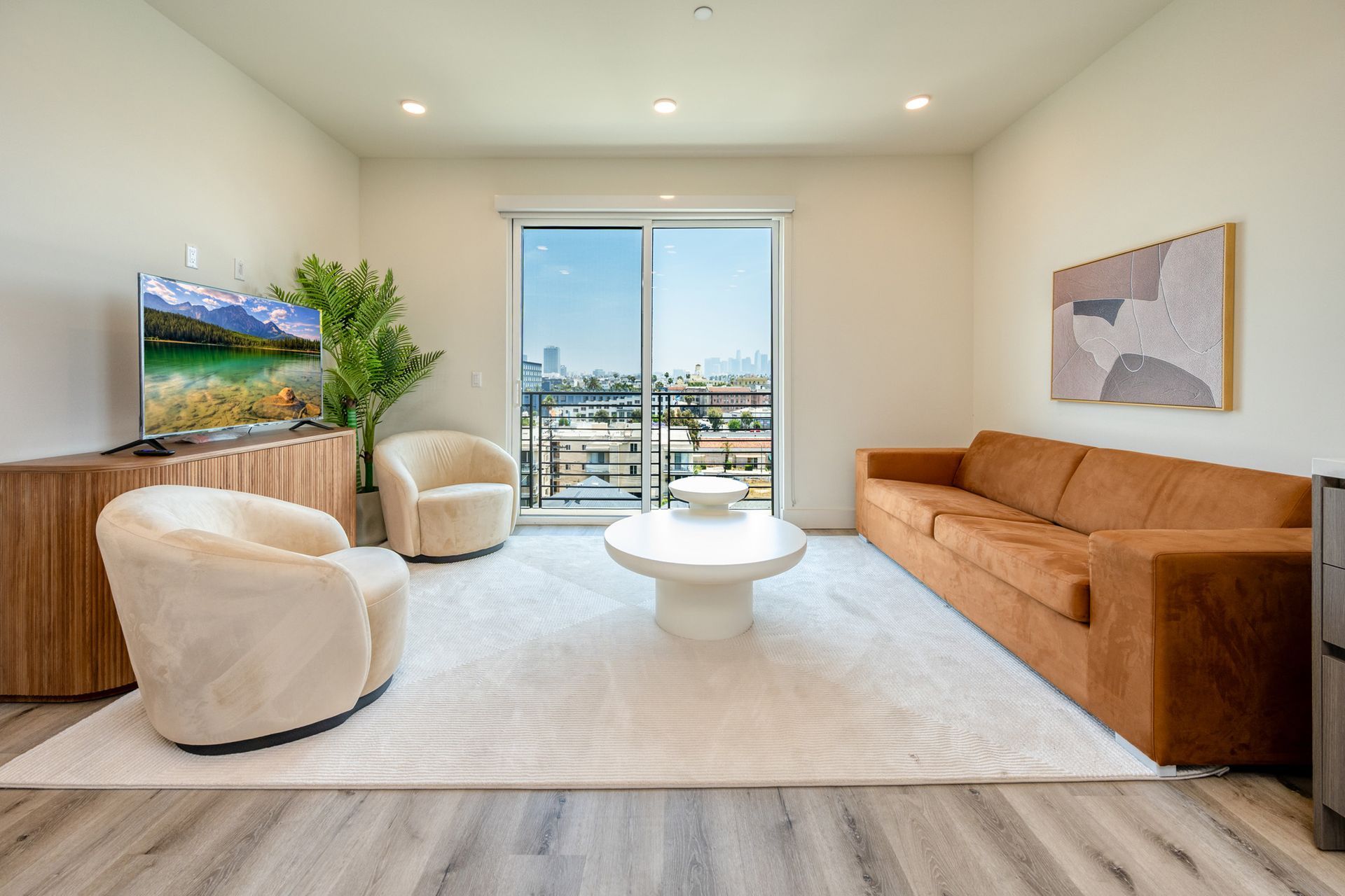 A living room with a couch , chairs , coffee table and television.