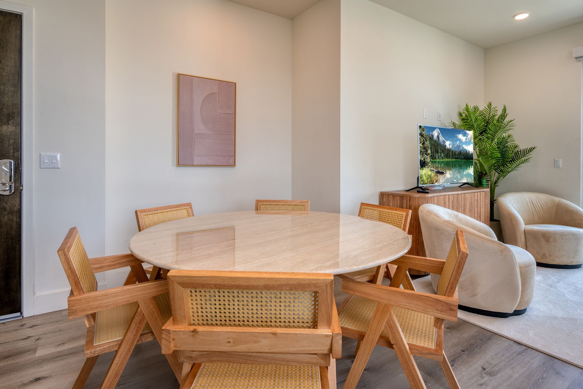 A dining room with a round table and chairs and a television.
