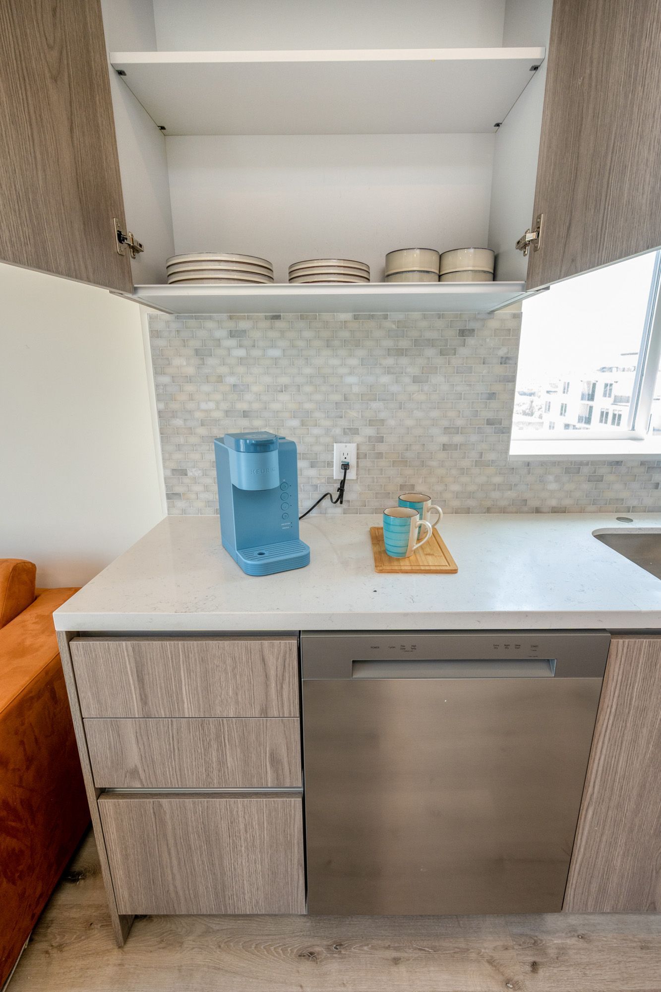 A kitchen with a stainless steel dishwasher and a coffee maker on the counter.