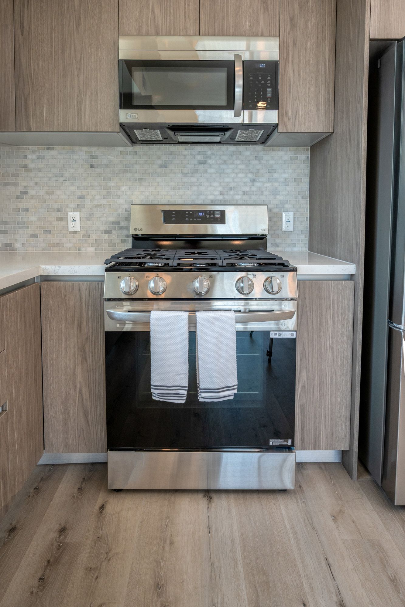 A kitchen with a stove , microwave , and refrigerator.