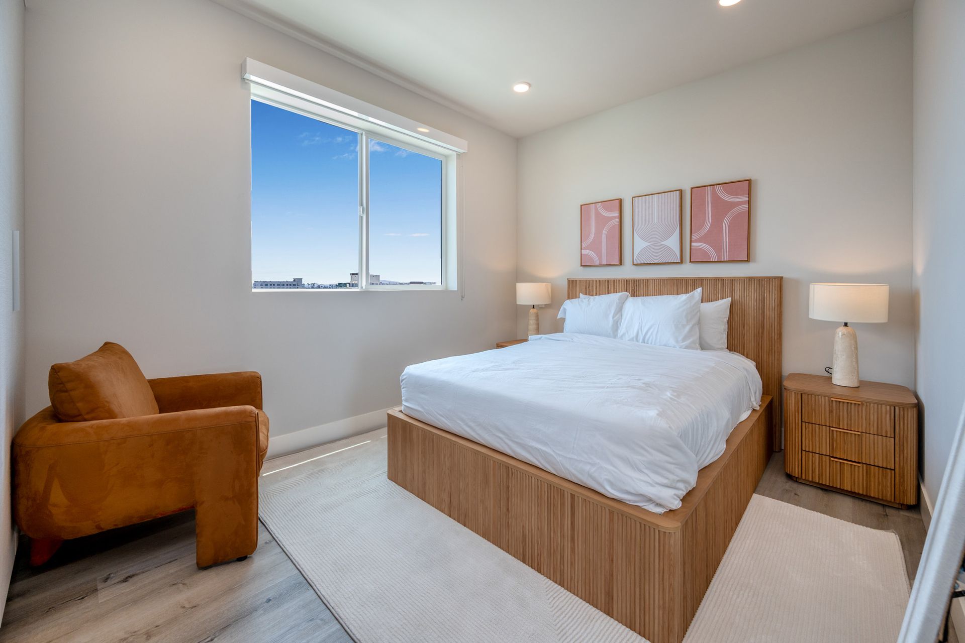 A bedroom with a bed , chair , nightstand , and window.