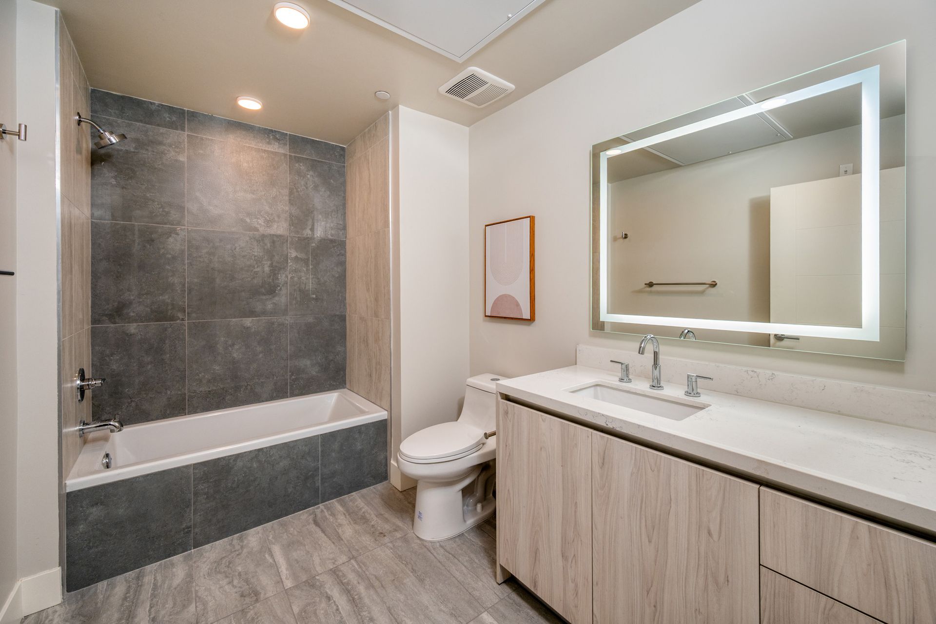 A bathroom with a toilet , sink , bathtub and mirror.