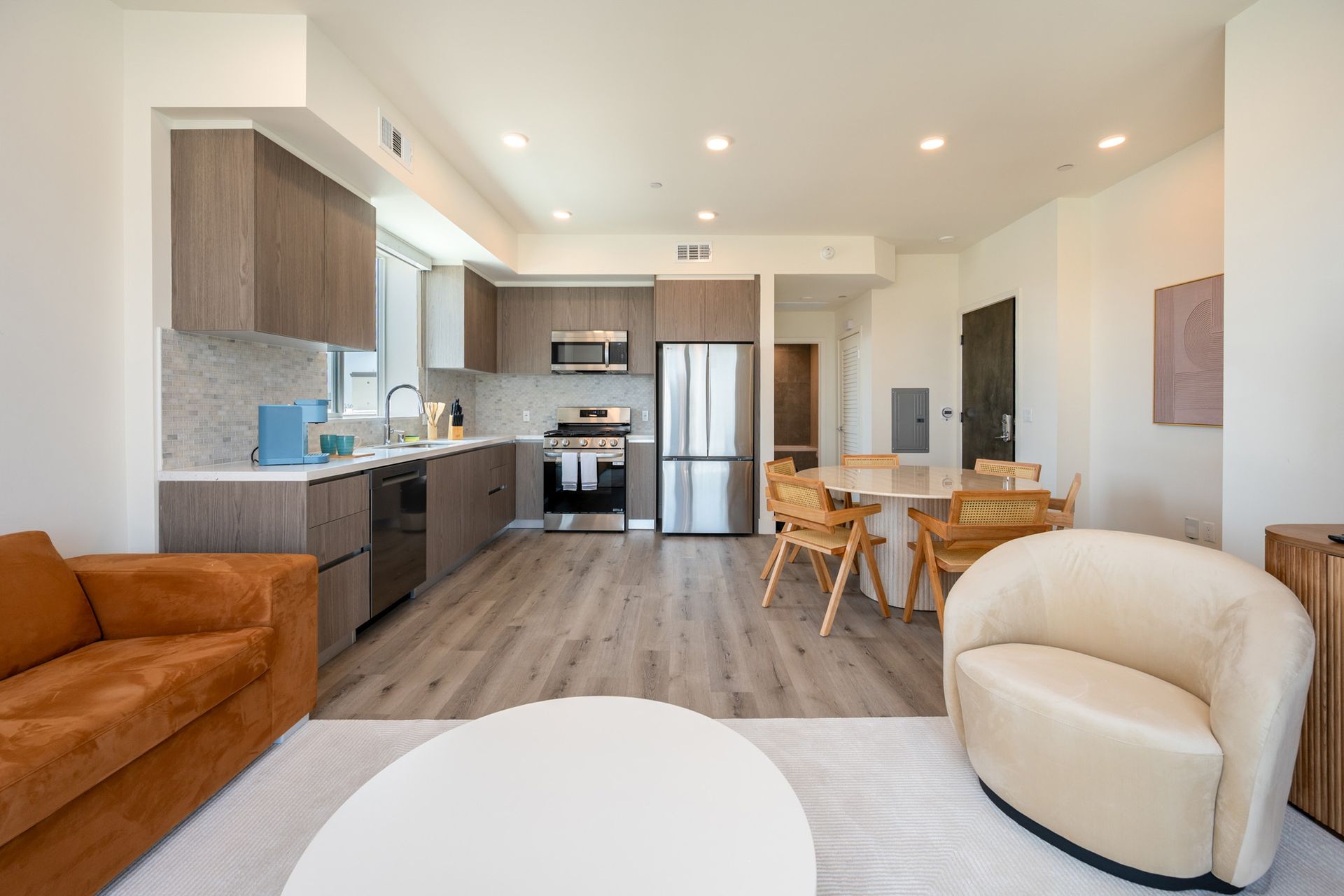 A living room with a couch , chair , table and kitchen.