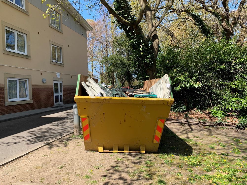 Yellow Dumpster Overflowing With Construction Debris in Front of a Building — Fat Boy Skips Townsville In Mount Louisa, QLD