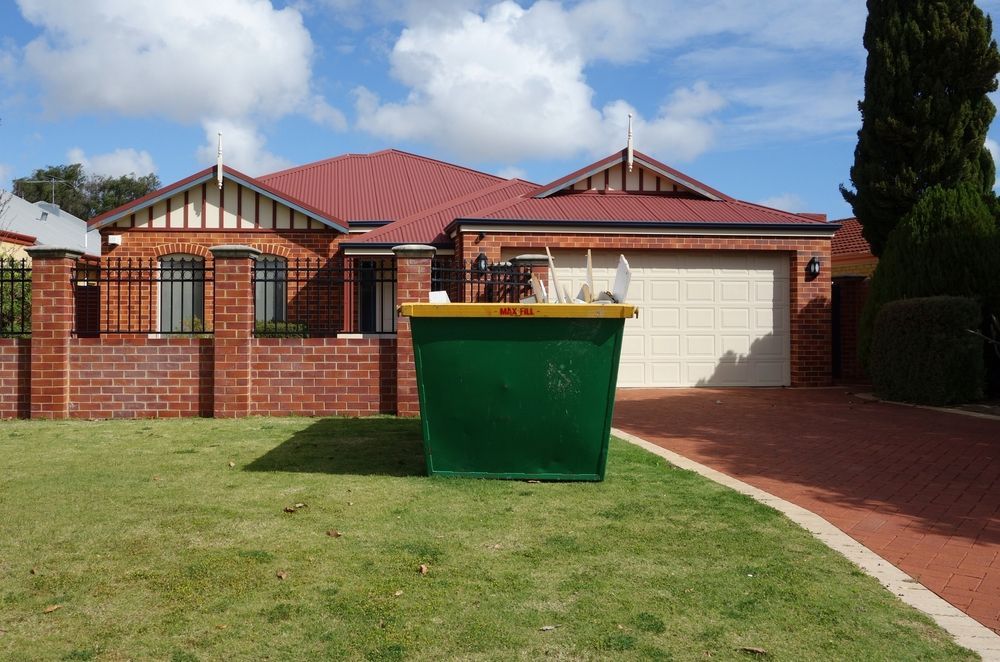 Green Dumpster on a Lawn in Front of a Brick House With a Red Roof — Fat Boy Skips Townsville In Annandale, QLD