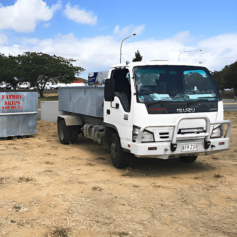 Skip Bin Beside a White Truck