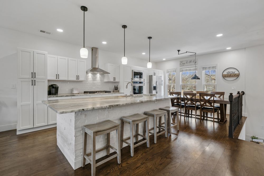 Bright modern kitchen with large island, white cabinets, pendant lights, and adjacent dining area