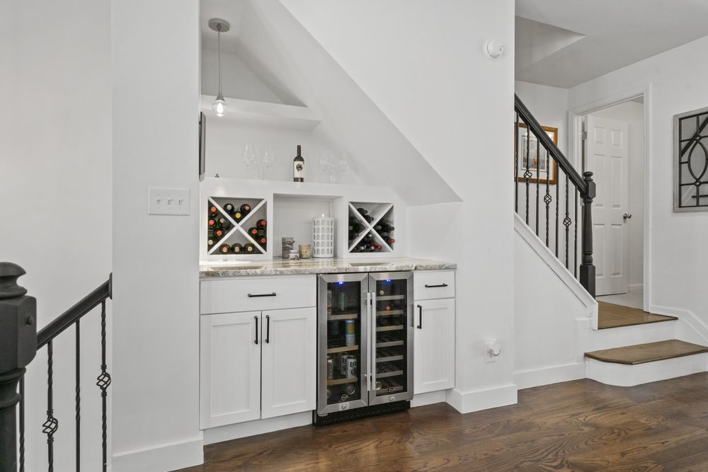 Built-in white bar nook with wine fridge and staircase in a bright modern home