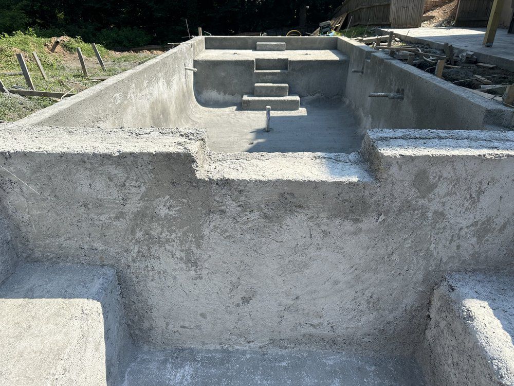 Concrete foundation with steps and raised walls in a construction site.