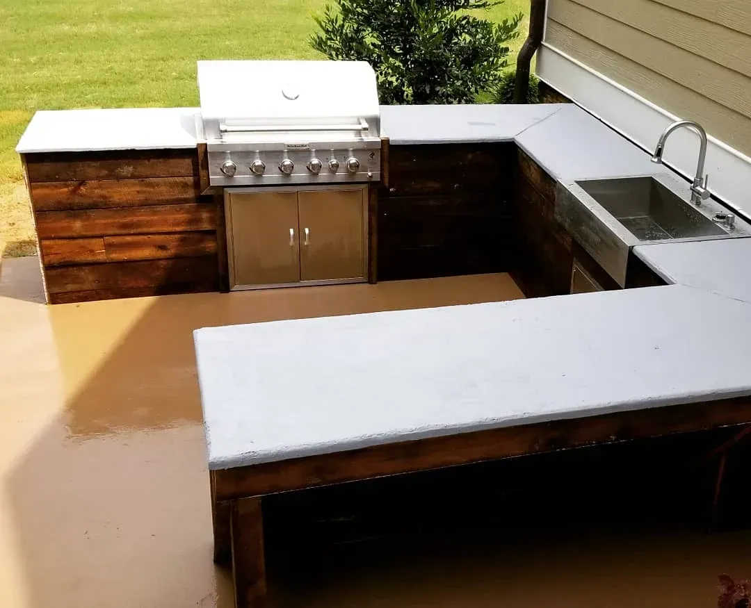 Flooded outdoor patio with an L-shaped grill counter and white-covered surfaces.