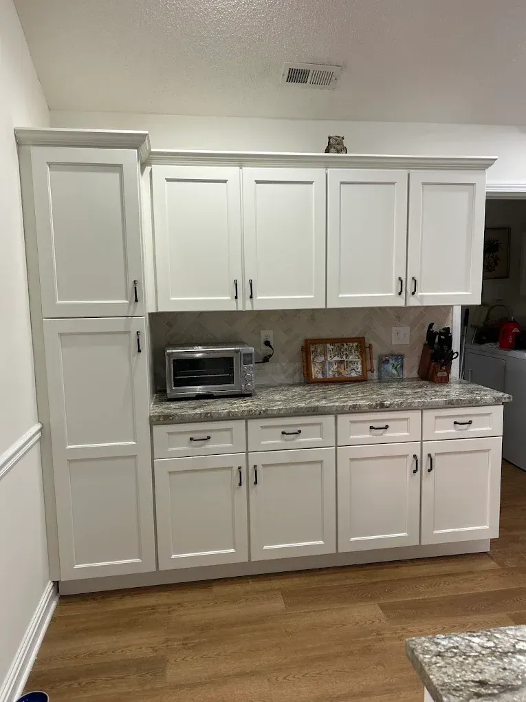White built-in kitchen cabinets with microwave, countertop decor, and wood flooring