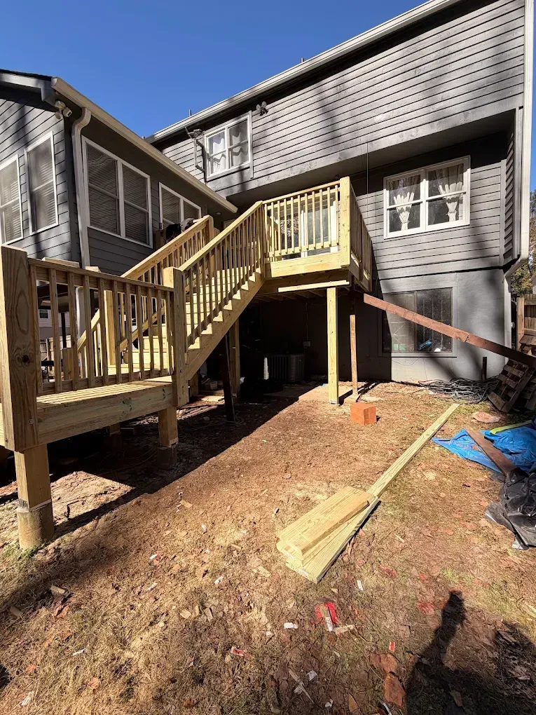 Wooden outdoor stairs and deck beside a house, with construction debris and tools in the yard.