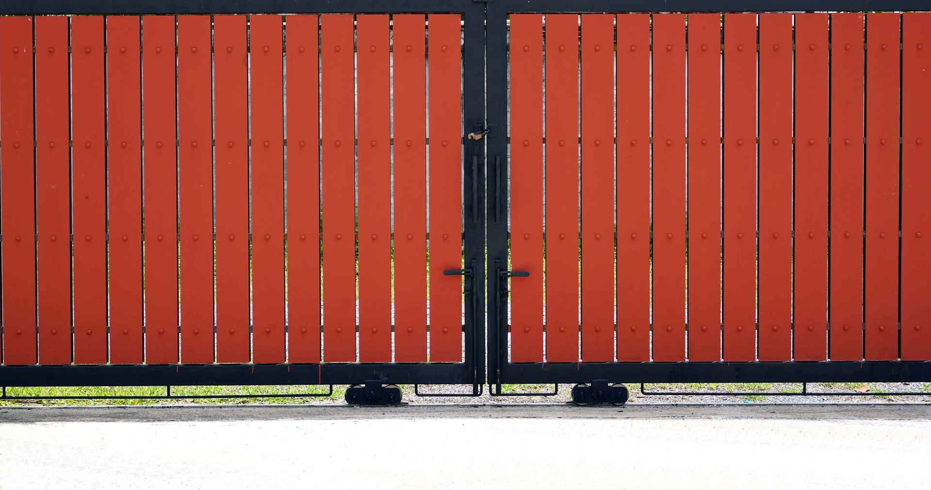 Red wooden fence gates, black frame, closed.