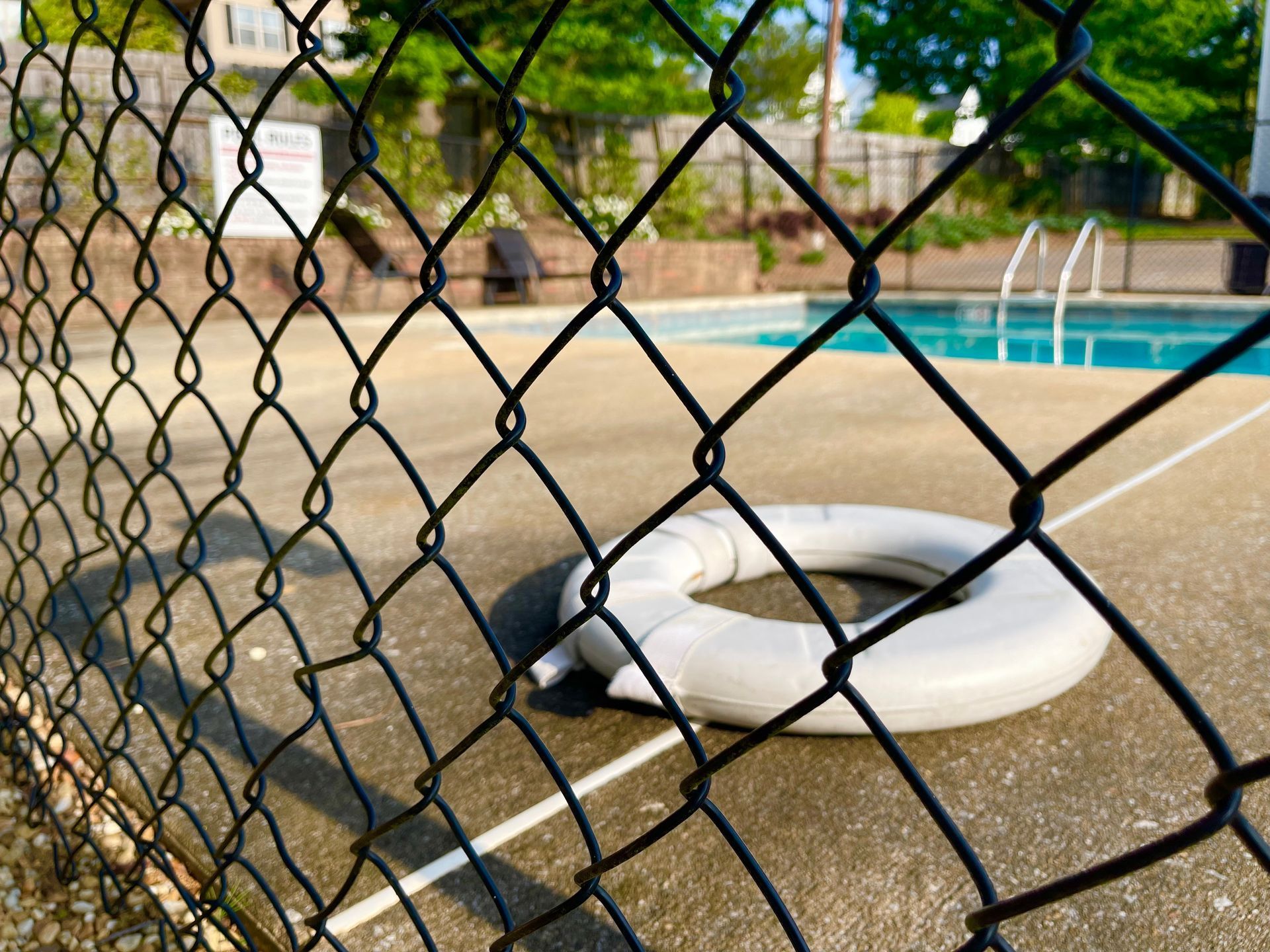 Chain link fence in foreground; pool and life preserver in the background.