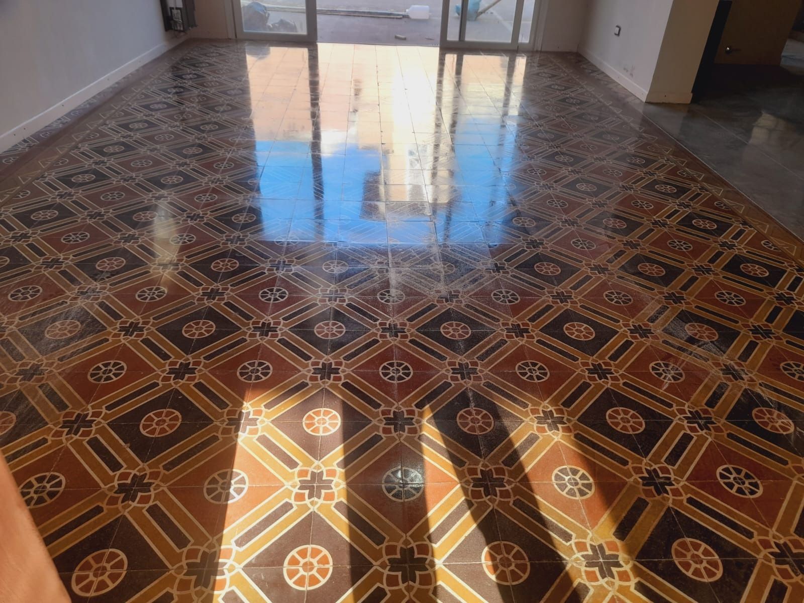 Piso brillante con patrón geométrico repetido de mosaicos en marrón, negro y tostado.