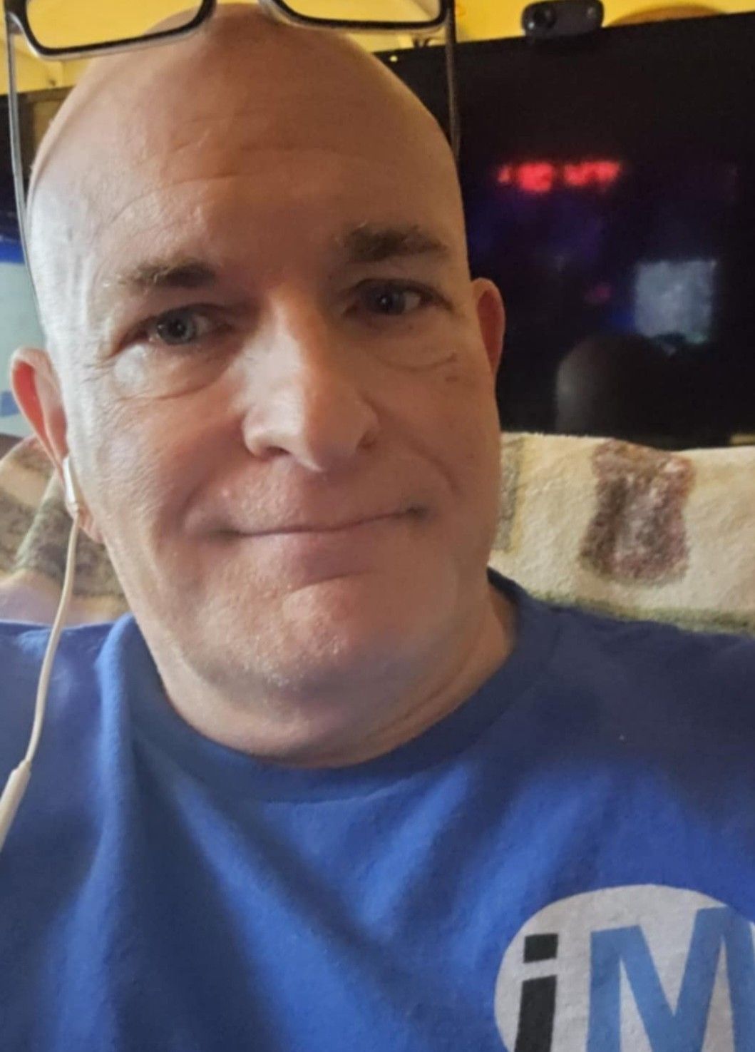 A bald man with a beard is wearing a blue shirt.