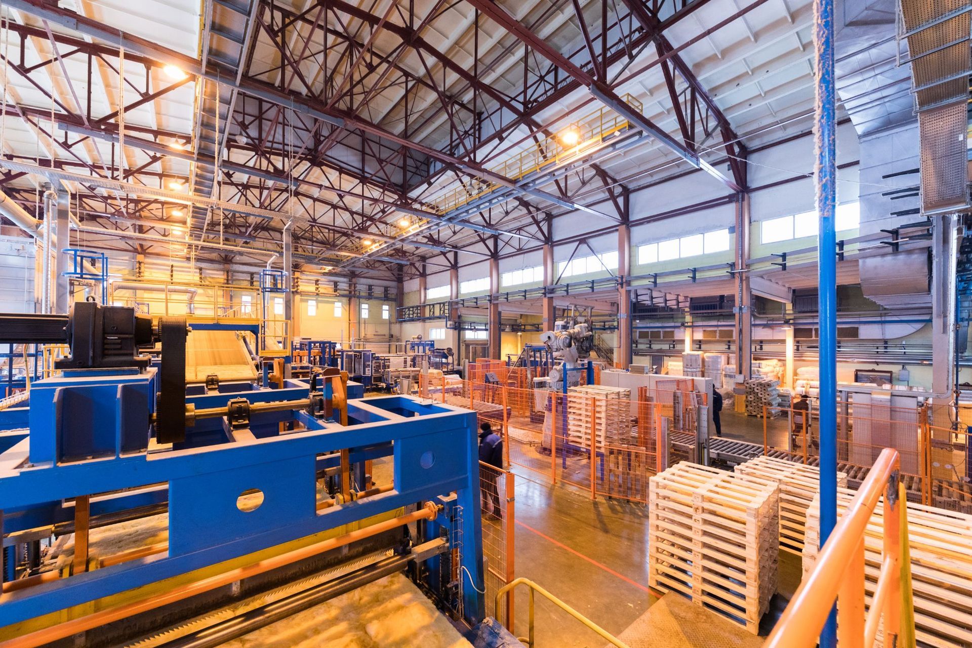 A large warehouse filled with lots of machinery and pallets.