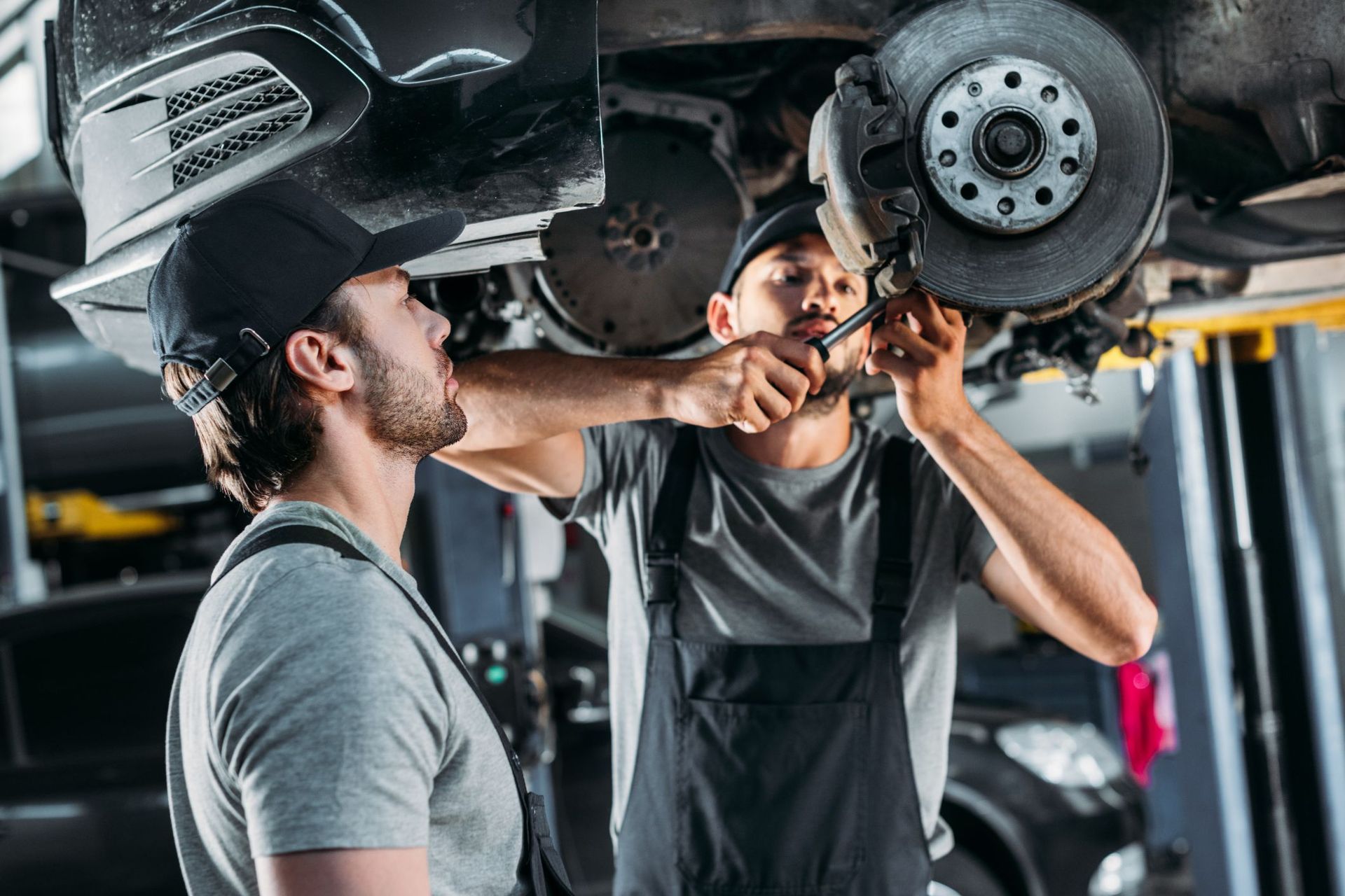 Two mechanics are working on a car in a garage.