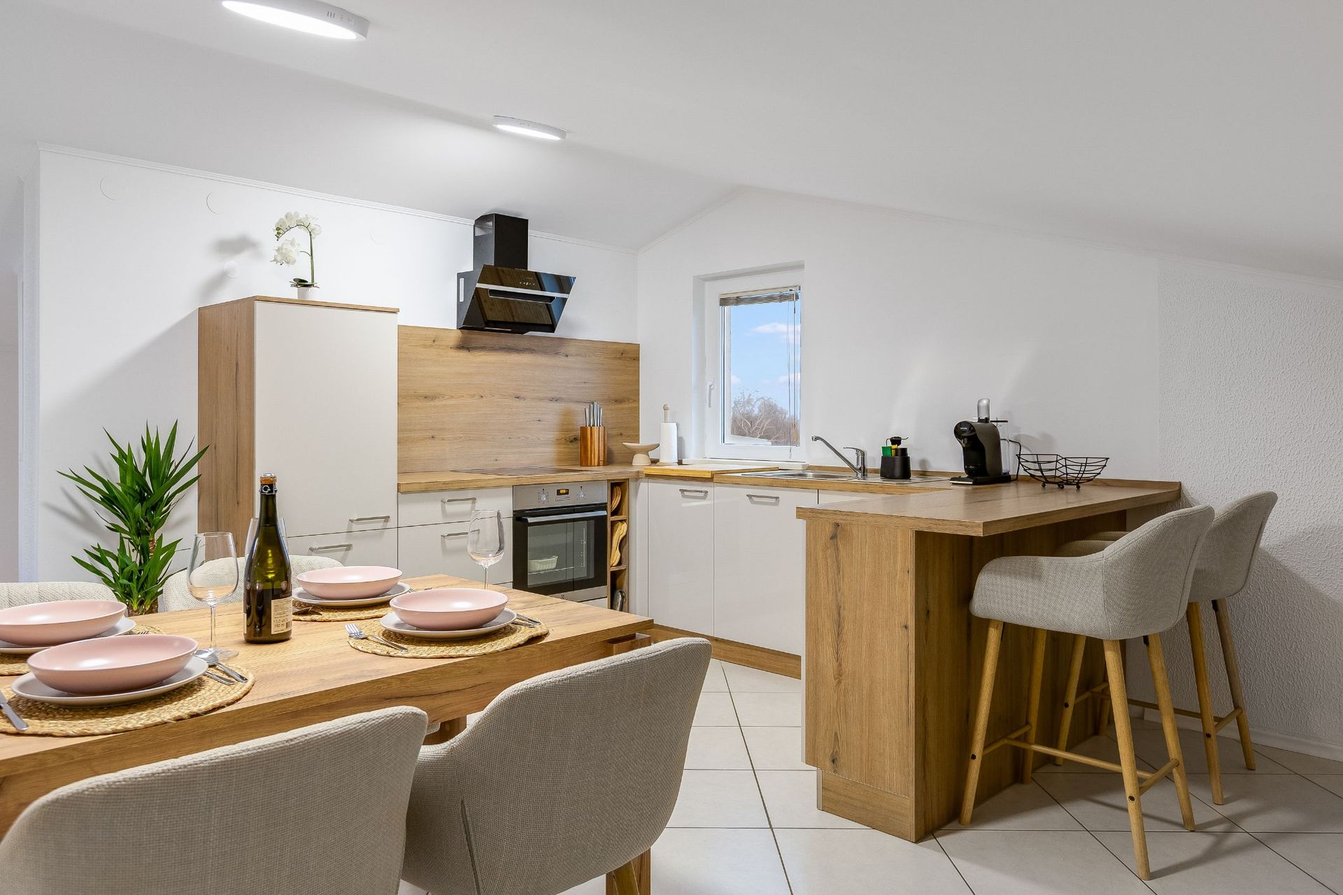 A kitchen with a table and chairs and a bottle of wine on the table.