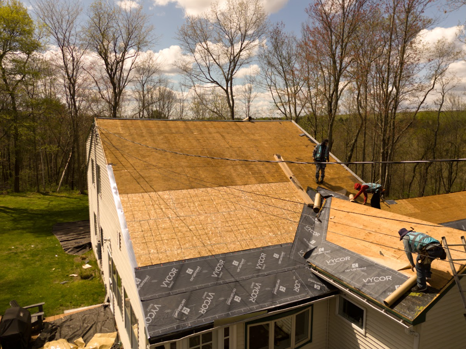Roofers installing a wooden roof on a house in a wooded area
