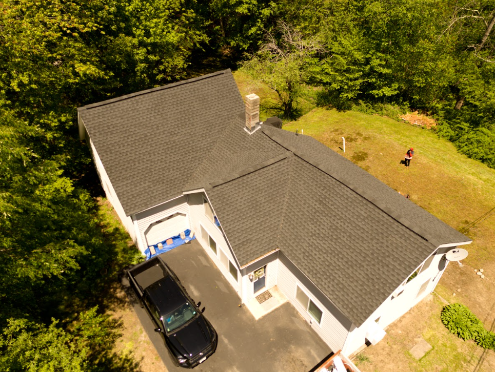 Black drone flying above a suburban house roof on a clear day