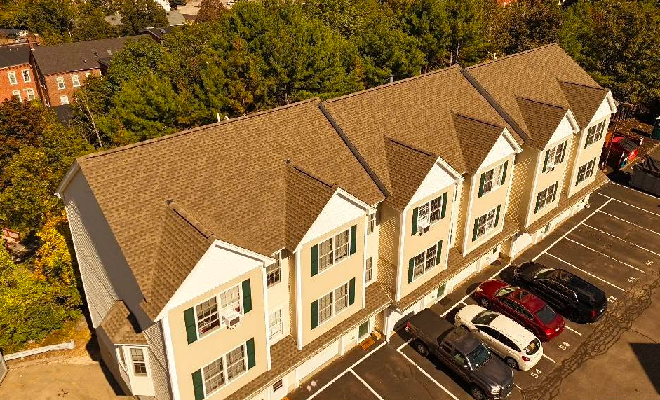 Black drone flying above a suburban house roof on a clear day