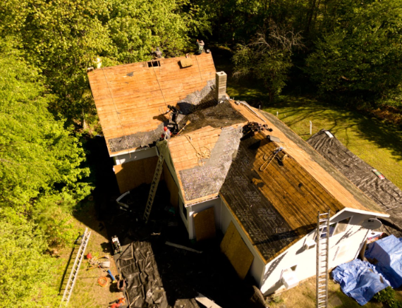 Flat black roof on a building with two vents, surrounded by trees under a clear sky