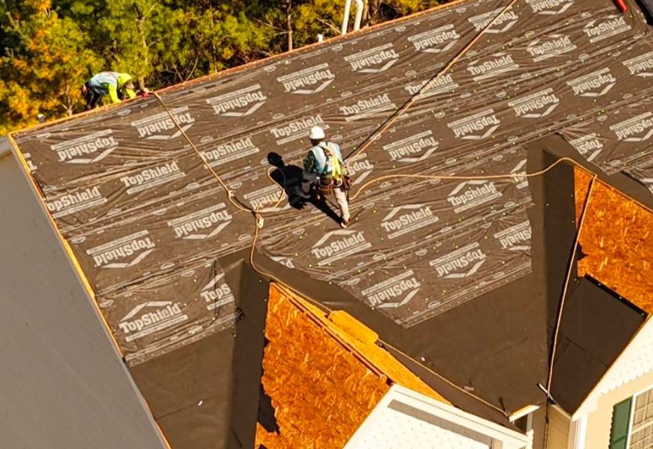Close-up of a dark shingled roof with a metal valley flashing at the center.