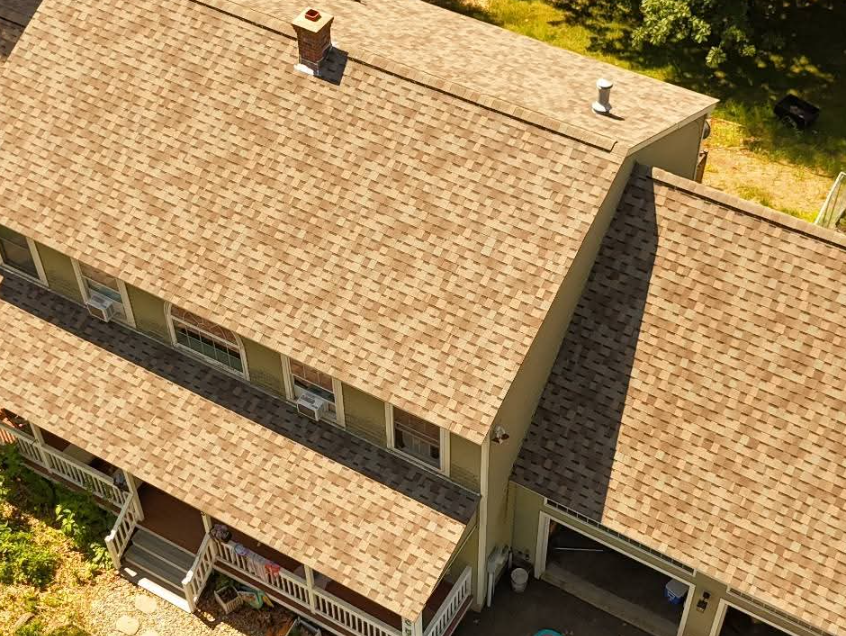 Flat black roof with two vents, seen from above, on a building surrounded by trees.
