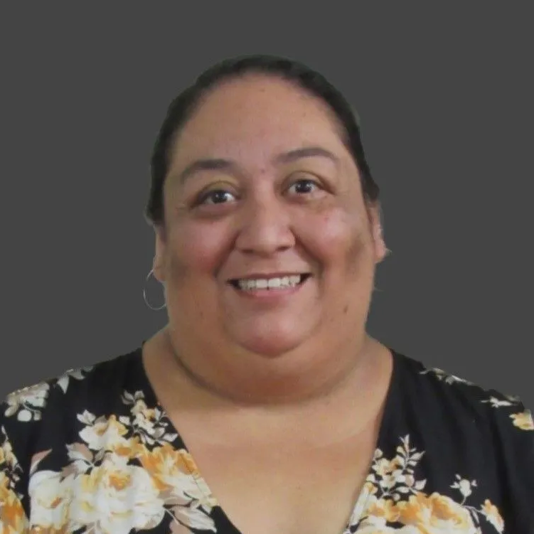 A woman wearing hoop earrings and a white shirt is smiling for the camera.