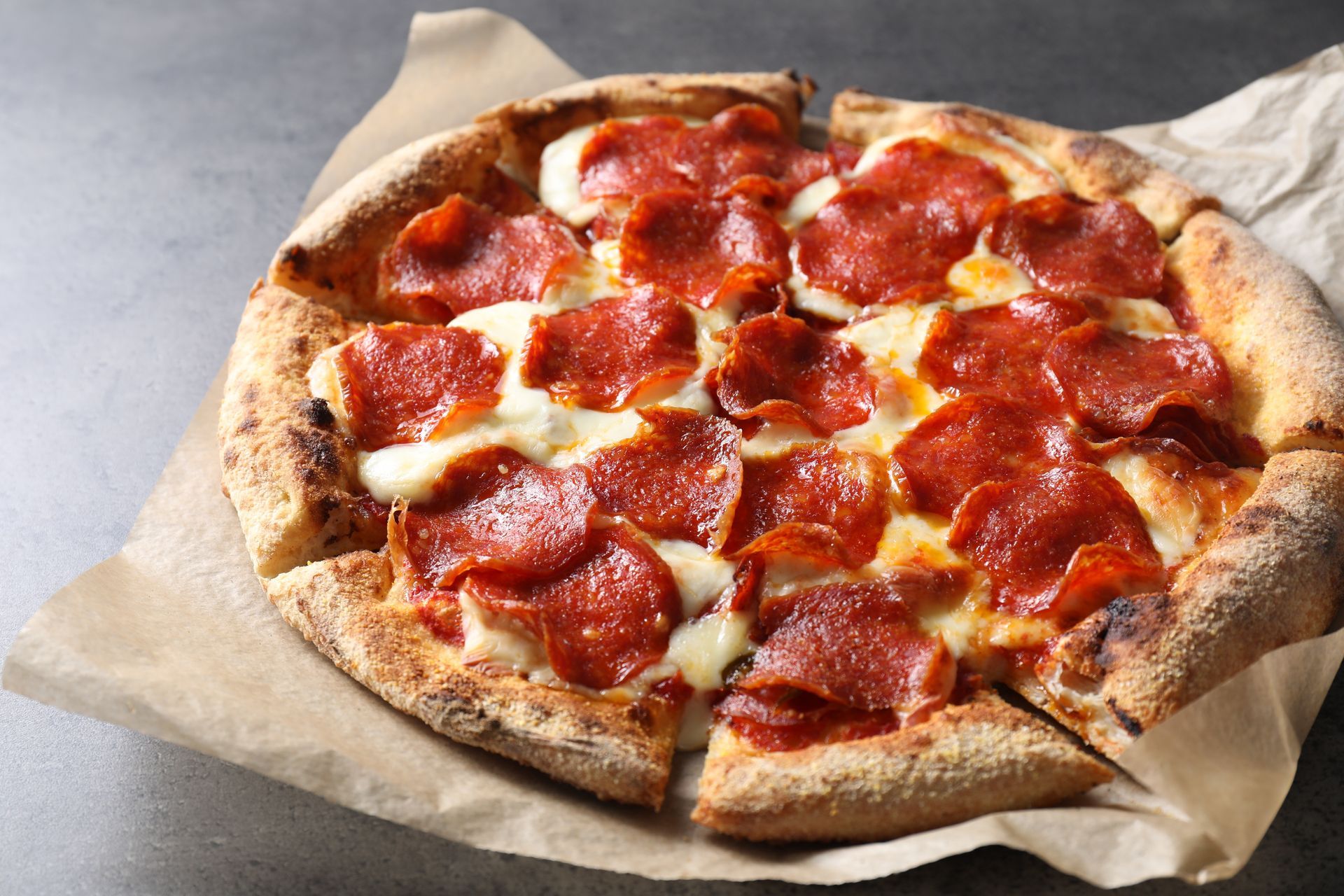 A pepperoni pizza is sitting on a piece of paper on a table.