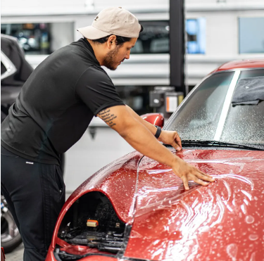 A man in a black shirt is working on a red car