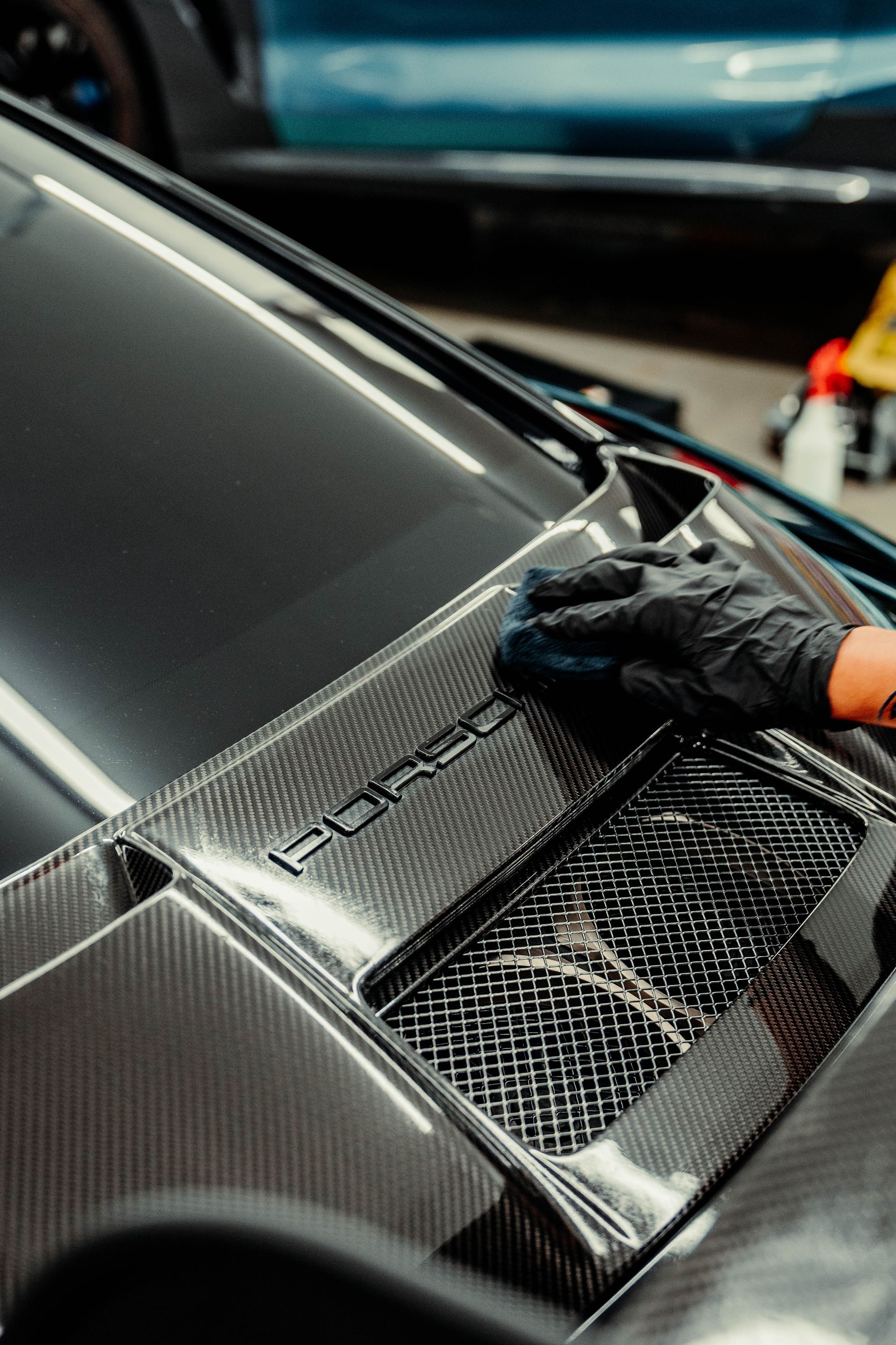 A person is cleaning the hood of a car with a cloth.