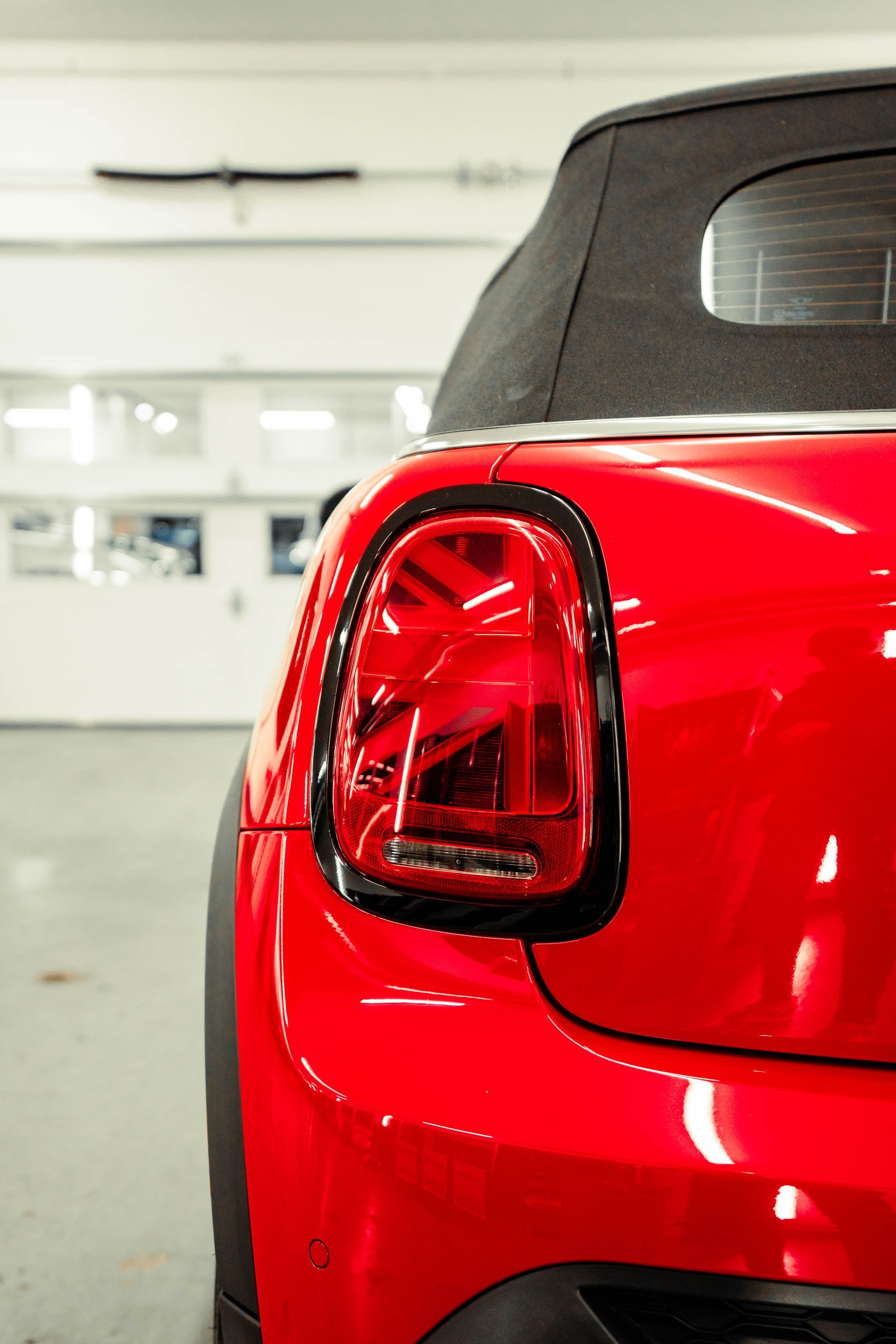 a red car with a black top is parked in a garage .