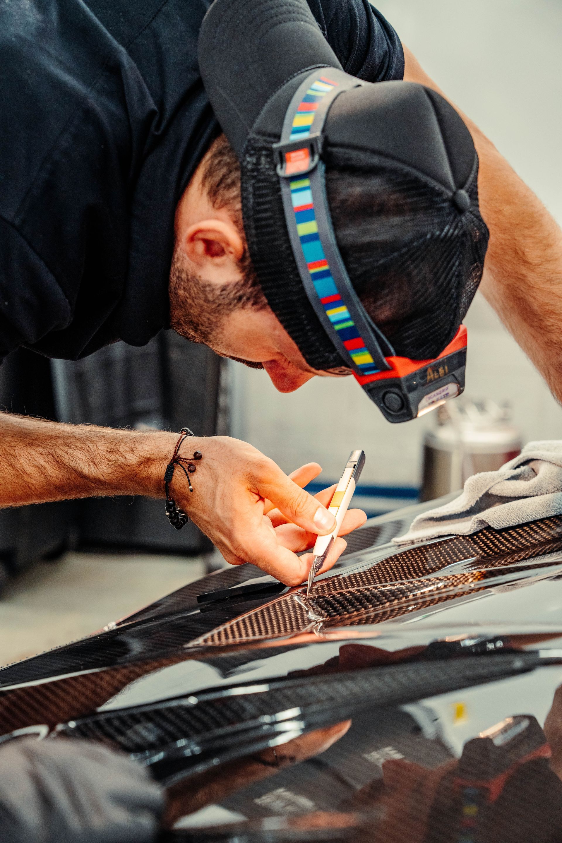 A man is working on the hood of a car.