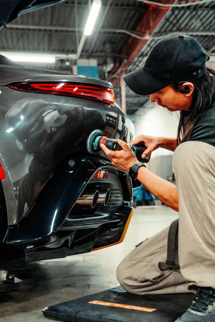 a man is polishing the back of a car in a garage .