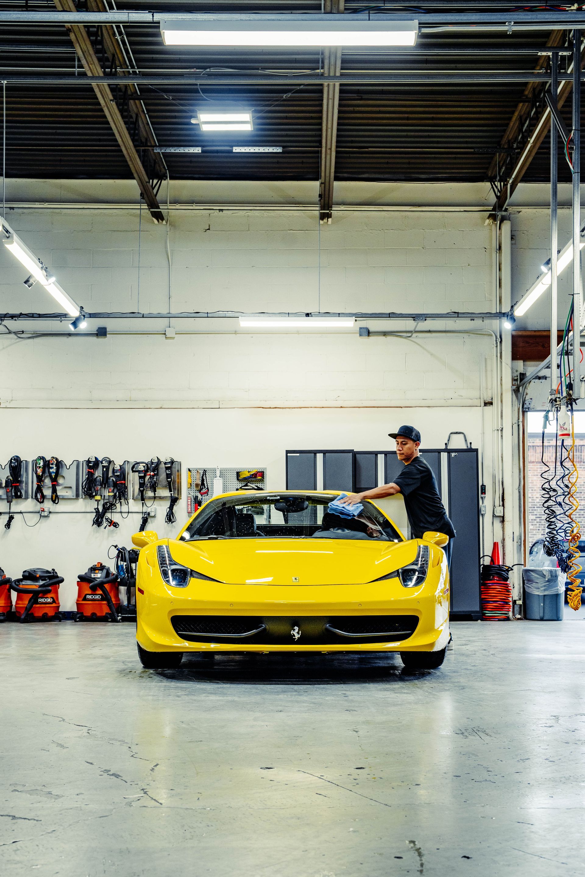 A man is working on a yellow sports car in a garage.