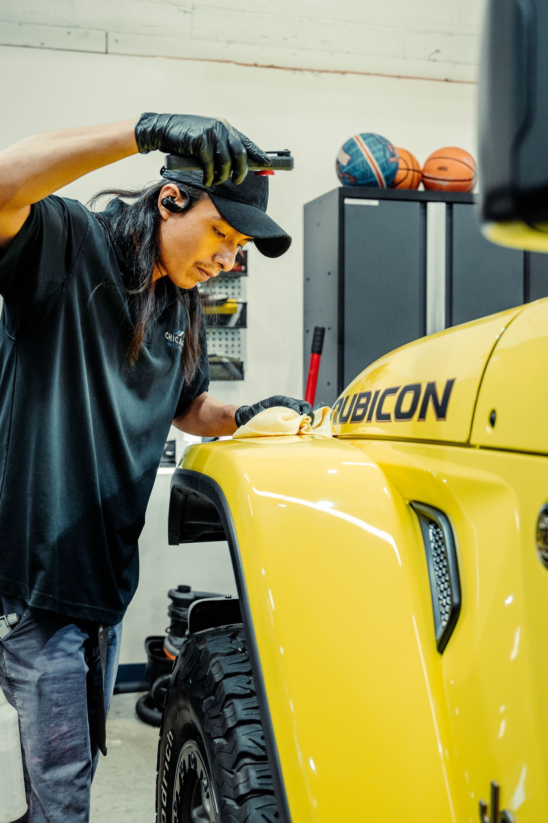 a man is working on a yellow jeep in a garage .
