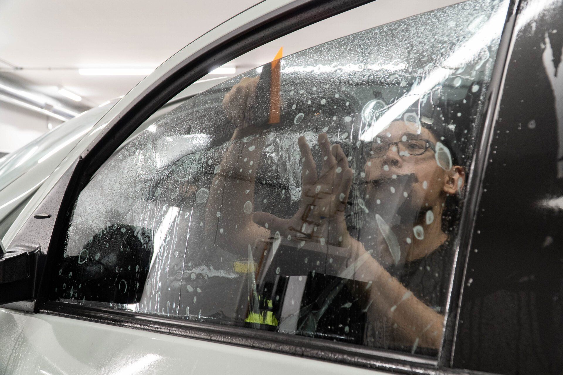 A man is applying window tinting to a car window.