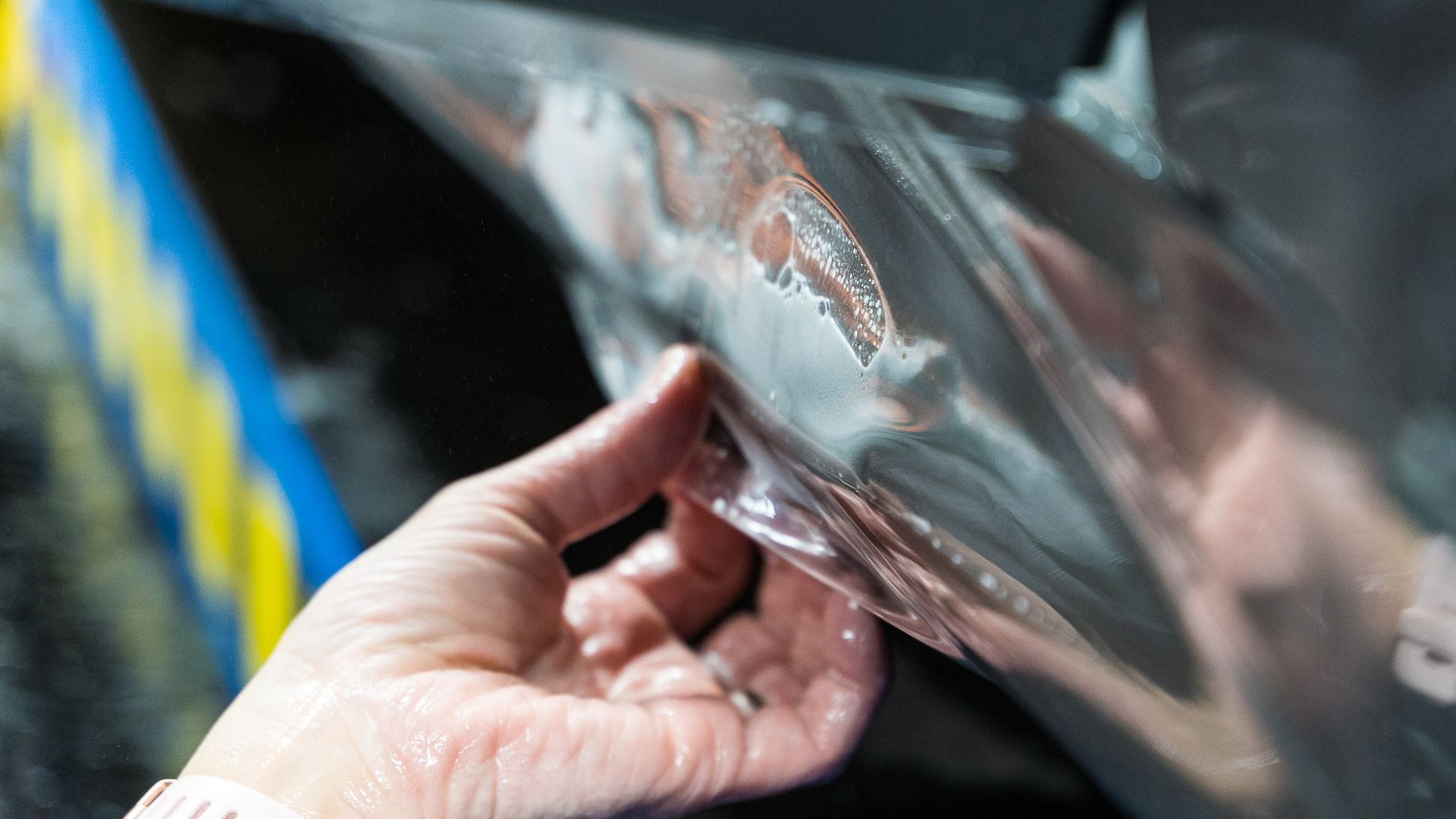 A person is holding a piece of plastic on a car.